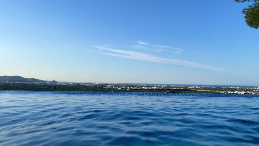 Panoramic view of Gandia in Rafelcofer, Valencia, during a sunny summer day, featuring a statue, trees, and a swimming pool, showcasing the beauty of the Valencian Community in Spain