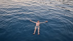 Relaxed person floats on his back in clear blue water at sunset. Serene Kemer coastal view with majestic Taurus mountains in the background. Summer holiday chill as man swims in the Mediterranean sea - Powered by Shutterstock - Get 15% off with code: PIKWIZARD15