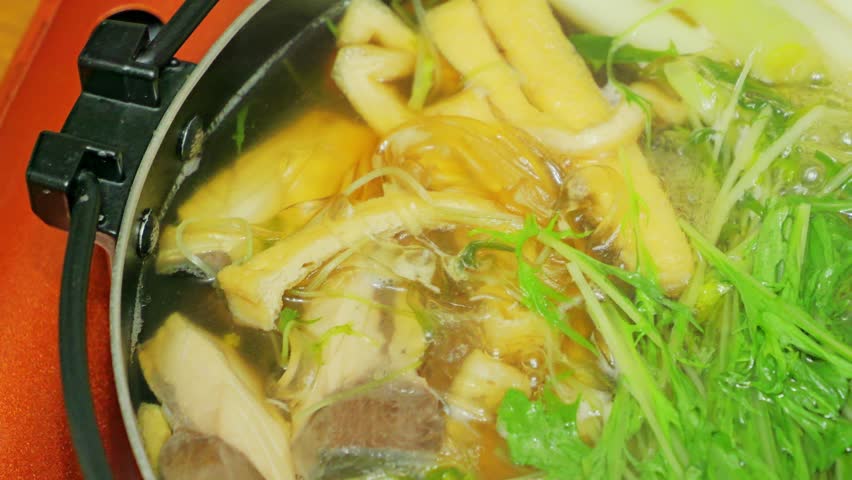 Japanese hot pot dish made with yellowtail fish, udon noodles, mizuna greens, and green onions