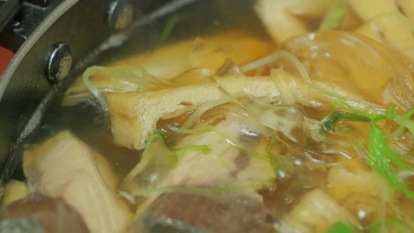 Japanese hot pot dish made with yellowtail fish, udon noodles, mizuna greens, and green onions