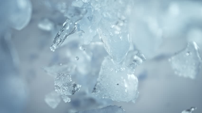 Super Slow Motion Shot of Ice Pieces Flying Towards Camera on Light Cold Background at 1000fps.