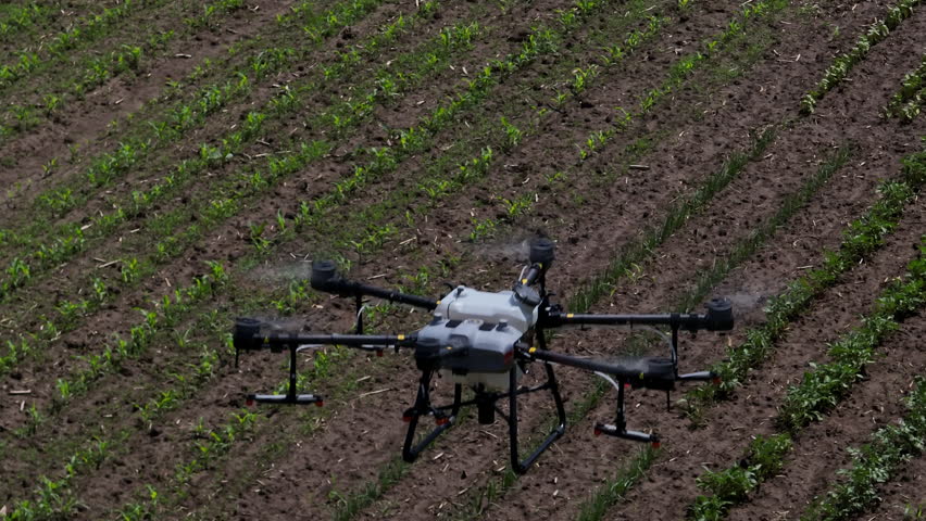 Aerial drone flying over a cultivated farm field during a crop monitoring or spraying mission, highlighting advanced agricultural technology and precision farming techniques in rural settings.