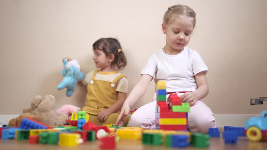 Two children playing with blocks. Group of children playing with lifestyle toys in a kindergarten. Constructors build a kindergarten together. Two kids engaging with building blocks.