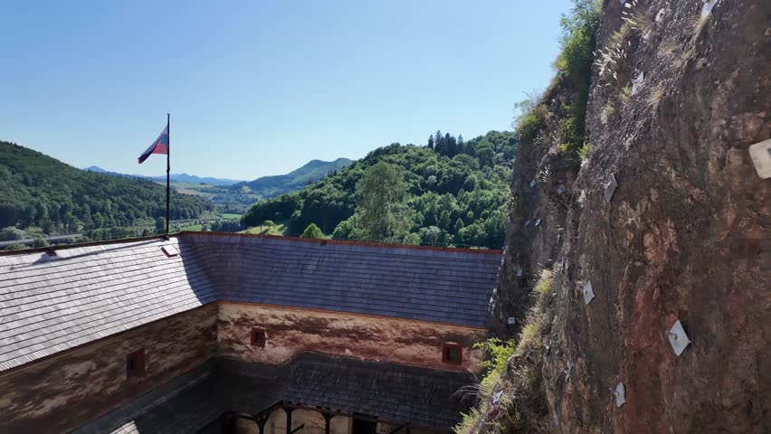Medieval Orawski castle Oravský hrad aerie Slovakia with a turret, white stone walls, fluttering flag and courtyard during a beautiful summer day - 4K