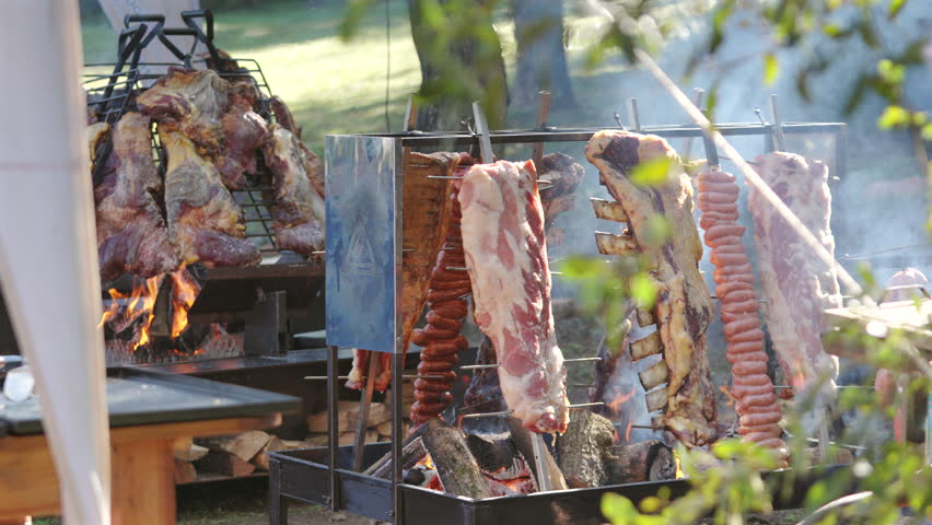 Roasting beef ribs on grills at rural Argentine barbecue, latin american food culture
