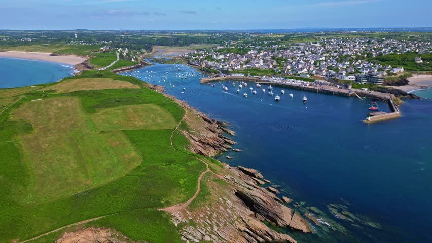 Le Conquet in Brittany, harbor with sailboats, sandy Plage des Blancs Sablons, green Kermorvan peninsula, France. Aerial forward