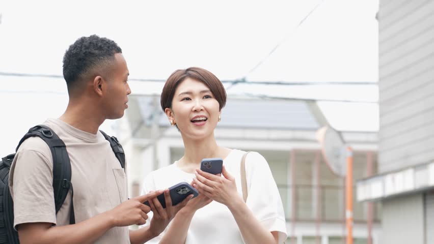 A Japanese woman conversing with a black man using a smartphone translation app