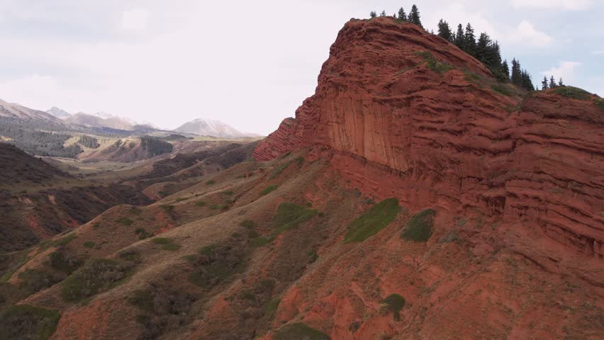 Stunning aerial view of the red rock formations in the Seven Bulls gorge, Kyrgyzstan. Layered rock faces and sparse vegetation create a dramatic landscape. Perfect for travel, nature, or geology
