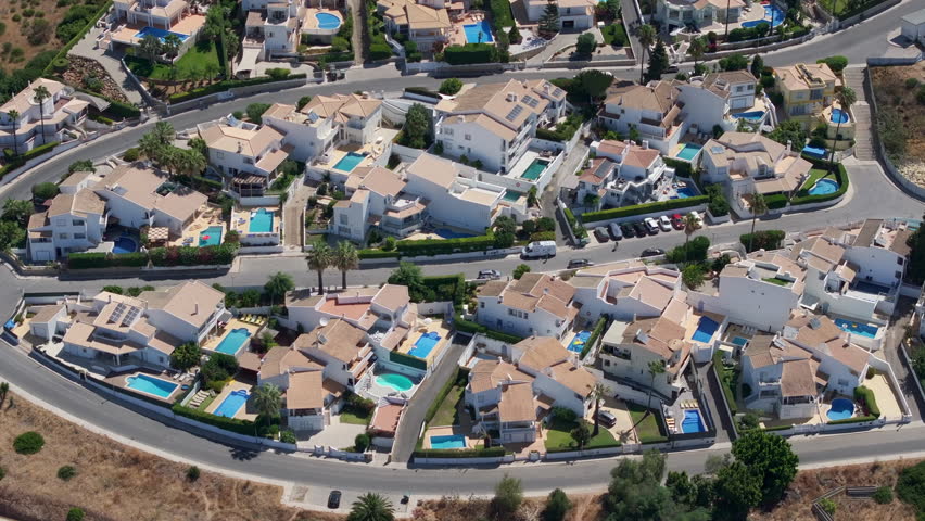 Aerial view of beautiful residential area with neighborhood houses and streets. Vacation homes with swimming pools, backyards and tiled roofs in Albufeira, Algarve coast, Portugal. 
