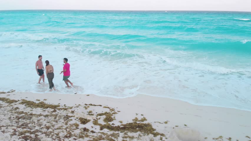 Vacationing travelers relaxing and walking on pristine white sand beach, enjoying crystal clear turquoise waters in scenic hotel zone of cancun, quintana roo, mexico