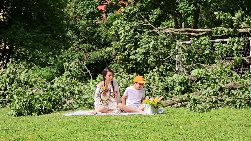 woman with son in white on grass picking berries, girl and boy in wreath with basket, outdoor recreation, travel, trip, mother and son picnic on grass, braids, brunette,