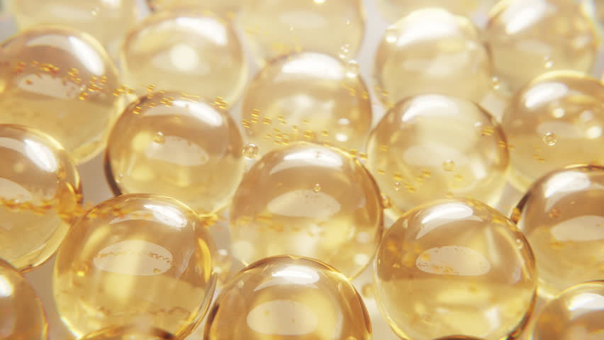 Macro shot of glowing collagen softgel capsules. Perfect for skincare, cosmetic, and supplement concepts. Shiny texture, transparent golden beads, luxurious and clean look.