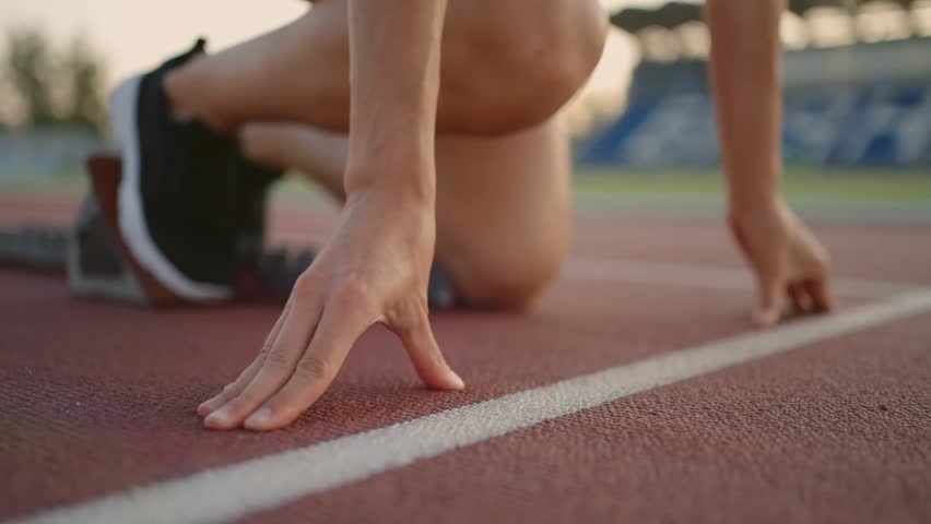 Young Woman Runner Prepares For Sprint At Stadium In Slow Motion