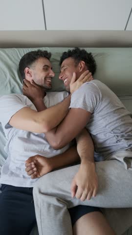 Slow motion montage revealing intimate moments of loving lgbti couple sharing tender embrace in bedroom, expressing deep emotional connection and genuine affection