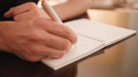 A close up shot of a person's hand writing something in English with a pen in longhand. The video has beautiful natural lighting and great visual aesthetic quality. - Powered by Shutterstock - Get 15% off with code: PIKWIZARD15
