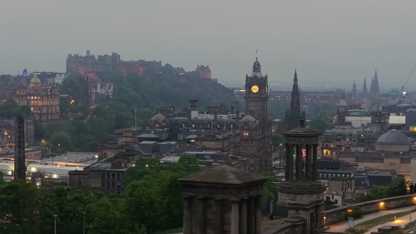 Cinematic drone footage of Edinburgh on a foggy afternoon with the historic castle in the background. Moody atmosphere, soft light, and iconic skyline