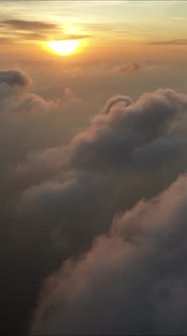 Aerial view of the sun setting, casting a warm glow over the fluffy clouds creating a breathtaking scene, Male, Maldives.