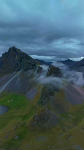 Majestic mountains rise in Iceland, cloaked in mystical clouds as lush valleys rest below. The dramatic landscape offers a serene escape, showcasing the beauty of nature in this Nordic paradise.
