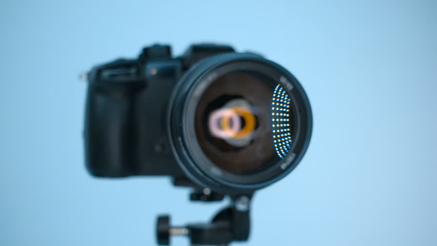 A professional camera on a tripod with an expensive lens with an aperture of 1.5 and a focal length of 85 mm, which reflects the ring LED light. Closeup. Macro. Shallow depth of field. Shot in motion