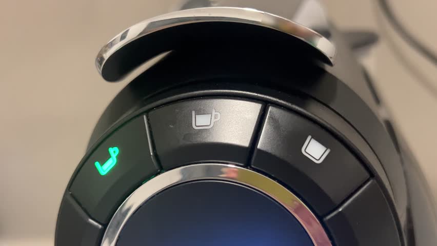 Coffee machine control panel with blinking green light, close-up view