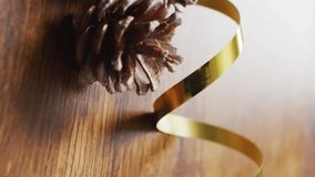 Pine cones with golden ribbon over heart shapes animation on wooden surface. Christmas, holiday, decoration, festive, pinecone, winter - Powered by Shutterstock - Get 15% off with code: PIKWIZARD15
