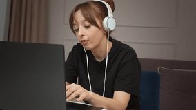 Female freelancer in noise-canceling headphones working remotely on laptop, participating in video calls emotionally and surprised, concentrating on professional task at home workplace - Powered by Shutterstock - Get 15% off with code: PIKWIZARD15
