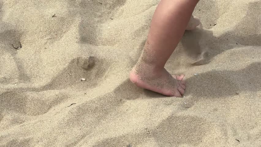 Unrecognizable child walks joyfully barefoot on a sandy beach, leaving footprints in the golden sand, capturing the pure joy of a day spent at the shore full of happiness and adventure, slow motion