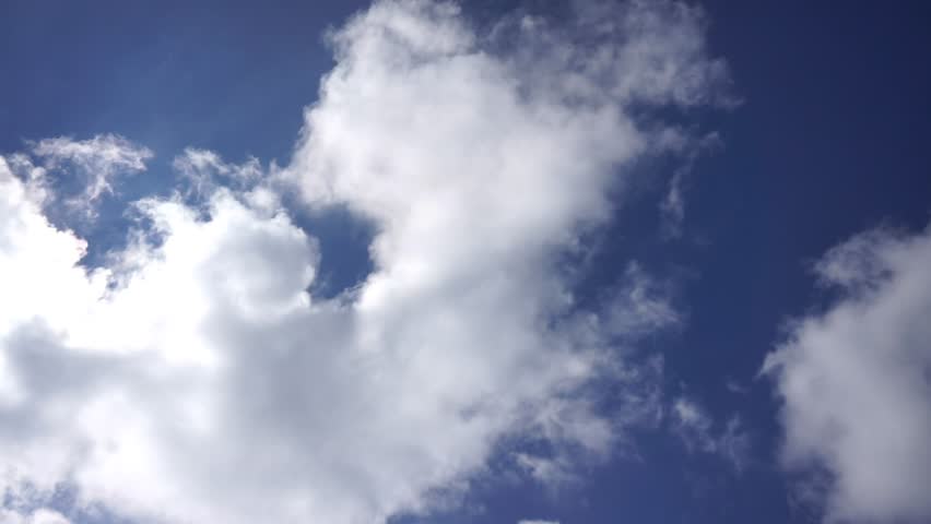 Timelapse of fluffy white clouds drifting across a deep blue sky, illustrating the beauty of nature and the passage of time