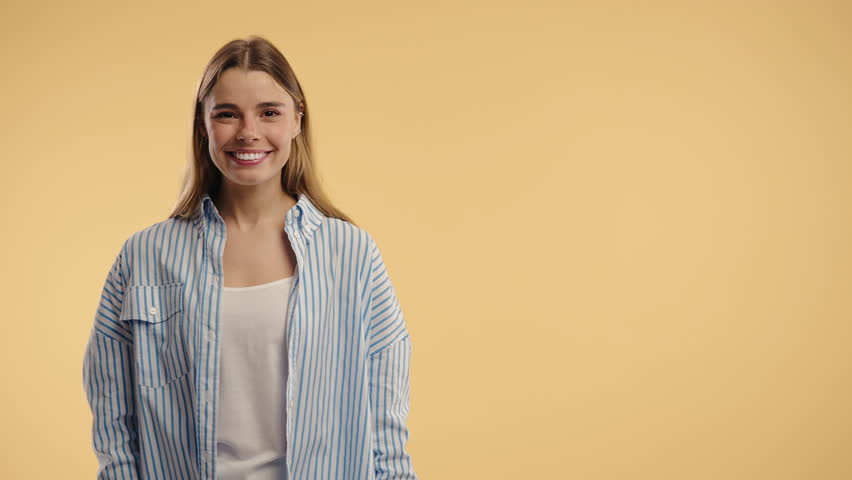 Happy smiling woman presenting and showing something isolated on beige background. Portrait of pretty lady, pointing with arms on copy space.