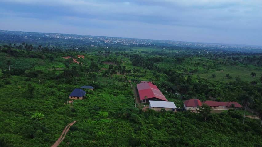 Beautiful aerial of a large farm surrounded by stunning lush and green nature in the countryside of Nigeria, Africa