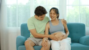 Happy asian husband and pregnant woman hugging belly, Hand of male touching pregnant wife's belly while sitting on the sofa at home, Mature loving couple expecting their first baby. - Powered by Shutterstock - Get 15% off with code: PIKWIZARD15