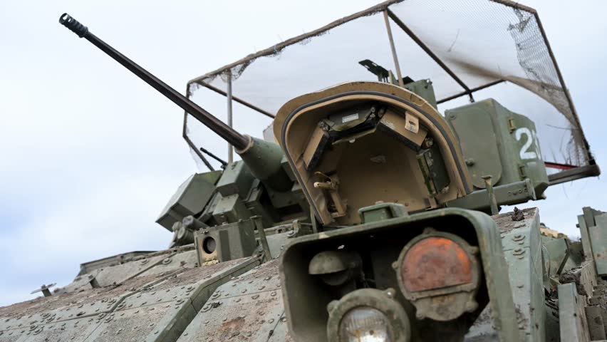 A low-angle close-up of the 25mm Bushmaster autocannon on a US-made M2 Bradley IFV during a training exercise in Ukraine. A 
