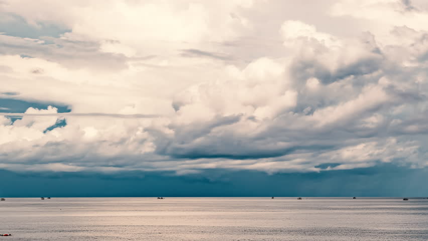 Cloudscape Evolution Over Calm Sea. Majestic Clouds Drifting Gracefully Over Tranquil Sea Waters. White and Gray Cumulus Clouds Looming Above Calm Sea Waters. Near Stormy Maritime Horizon