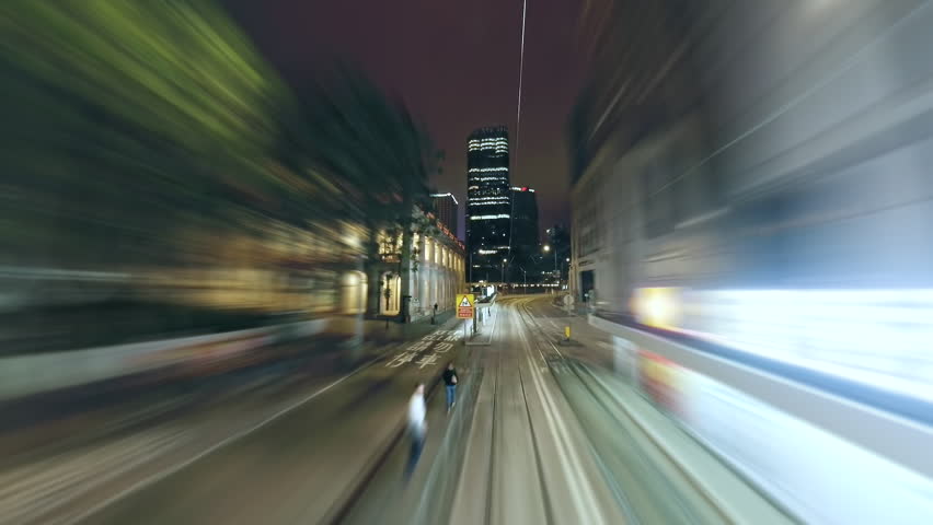 Hong Kong Tram's Rapid Journey Through Illuminated City Streets at Night. Fast Tram Crossing Hong Kong Streets at Night, Capturing the Vibrant Energy and Dynamic Movement of Urban Transit