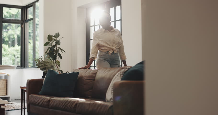 Black woman, homeowner or interior design with sofa for clean restoration or home improvement. Female person, owner or decor with leather couch for furniture choice, selection or comfort in new house