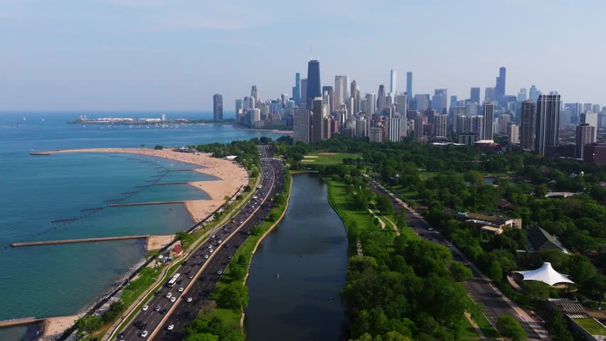 Aerial Pullback Reveals Lush Green Park with Chicago Skyline in Background. Lake Michigan
