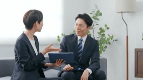 A group of male and female business people discussing business in a lobby while looking at a tablet - Powered by Shutterstock - Get 15% off with code: PIKWIZARD15