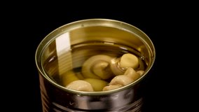 A stream of water splashes into an open can of champignon mushrooms, creating bubbles and ripples under bright studio lighting against a black background - Powered by Shutterstock - Get 15% off with code: PIKWIZARD15