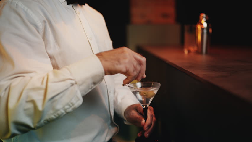 Suspicious male pub worker drugging Martini, illegal activity at bar counter