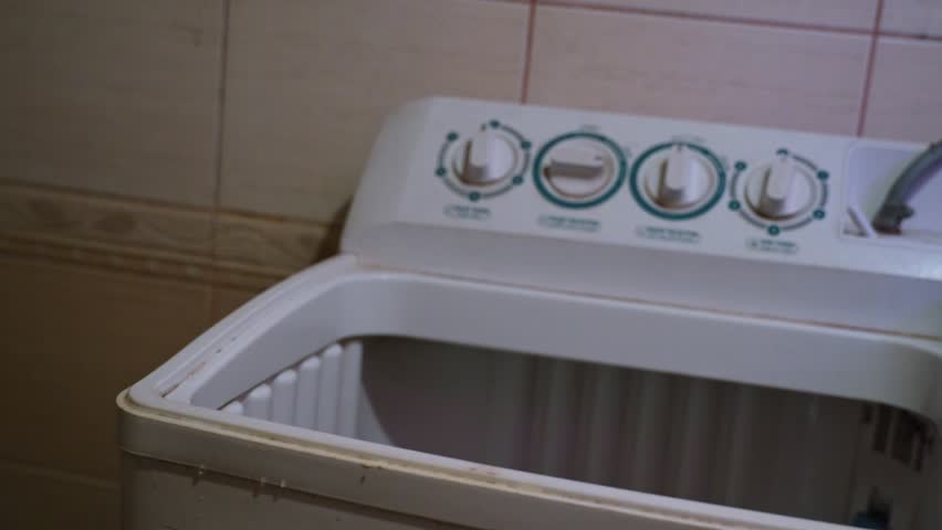 Close-up shot of washing powder being poured into a top-load washer—ideal for cleaning, hygiene, or household themes with realistic motion and appliance detail.