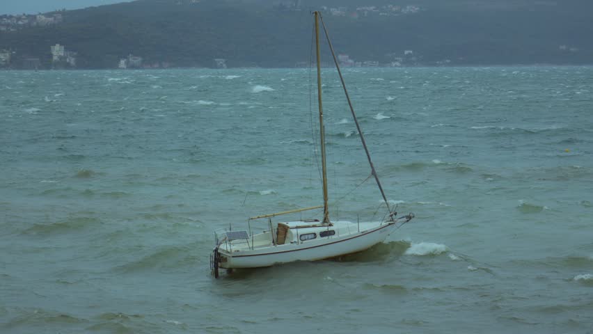 Sailboat struggles against waves in during a storm
