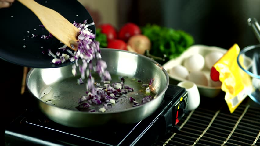 Chopped red onions being added into hot frying pan with oil. first step   delicious homemade cooking process. home cooking healthy food preparation. Kitchen ingredients organic food. Fresh vegetables