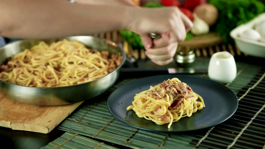 Italian pasta carbonara being seasoned with freshly ground black pepper. creamy spaghetti, topped  crispy pancetta, richness and flavor authentic homemade dish. Pasta carbonara appetizing Italian food
