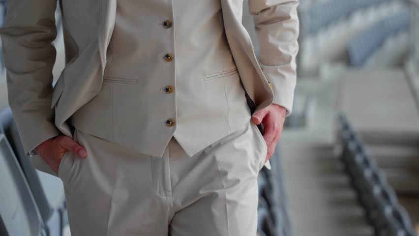 Close-up of a groom adjusting his beige suit and vest, preparing for a wedding ceremony. A stylish and elegant moment captured before the special event.
