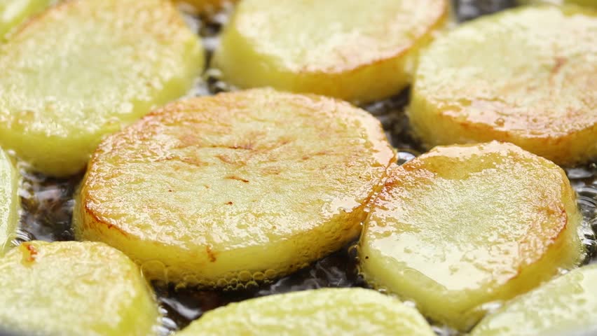 Pan-frying potato slices in hot oil. Close-up view