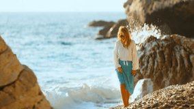 Woman enjoying a peaceful stroll along the rocky beach with gentle waves splashing in the background - Powered by Shutterstock - Get 15% off with code: PIKWIZARD15