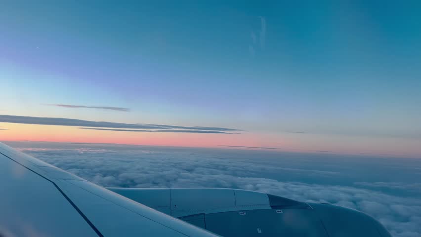 Airplane window view of Pastel pink horizon on morning sunrise blue sky, orange yellow cloud n fluffy cloudscape, aircraft wing above cloudy weather, 4k cabin passenger seat n aeroplane part backgroud