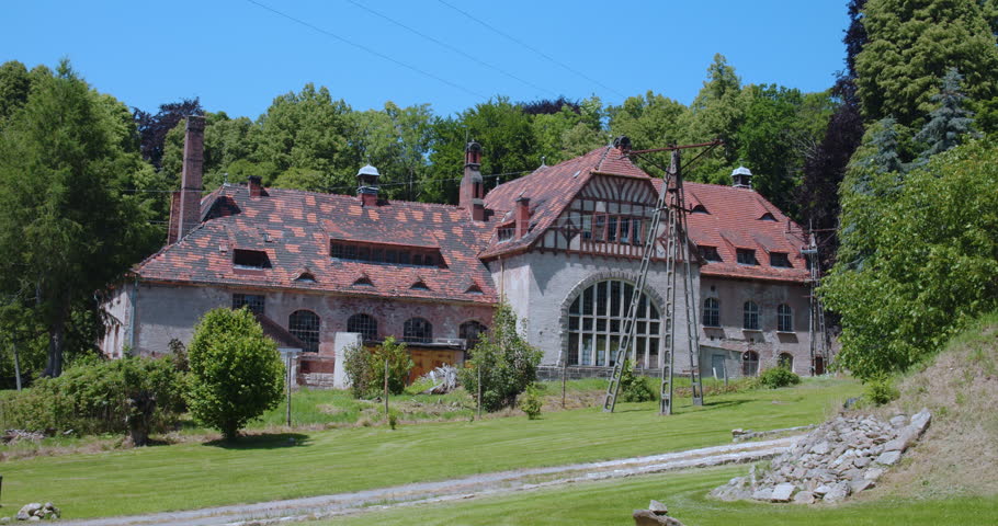 Old abandoned building with brick roof surrounded by forest