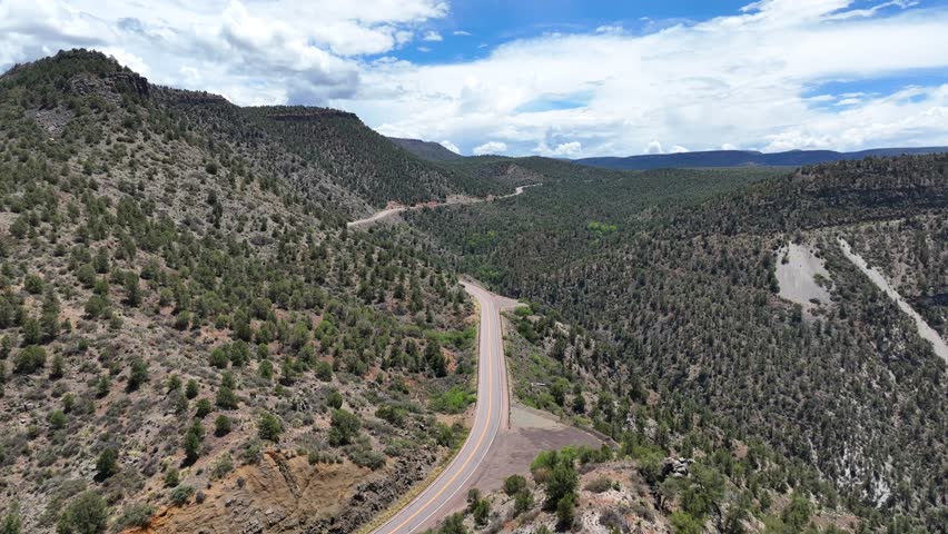 Aerial view of winding roads cutting through the rugged terrain of Salt River Canyon under a vast sky, showcasing nature