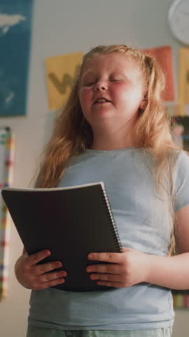 Renewable Energy Lesson: Elementary School Girl Holding Notebook Speaking, Giving Presentation on Geography in Front of Classmates. Student Showcasing Knowledge of Ecology. Dolly Shot. Vertical Shot.